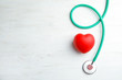 Stethoscope and red heart on wooden background, top view with space for text. Cardiology concept