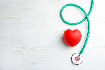 Stethoscope and red heart on wooden background, top view with space for text. Cardiology concept