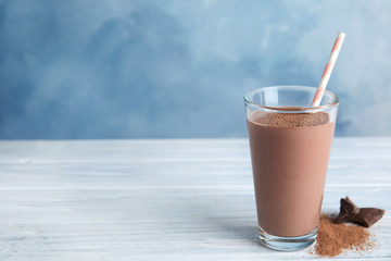 Glass with tasty chocolate milk on wooden table, space for text. Dairy drink