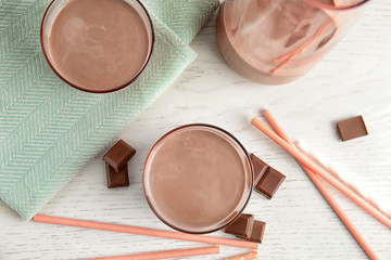 Flat lay composition with glasses of tasty chocolate milk on wooden background. Dairy drink