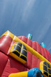 A giant colorful inflatable slider with joyful kids running up and down the slider in the fun park with happiness.