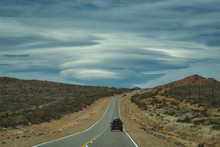 Vehicle Driving Away Through A Desert Landscape