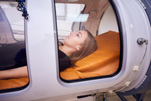 A Girl In A Black T-shirt Lies In A Hyperbaric Chamber, Oxygen Therapy, A Medical Room