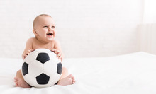 Newborn Baby Sitting With Soccer Ball On Bed