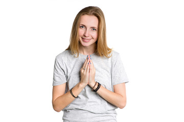 Wall Mural - Portrait of a young woman who is holding her hands in front of her in greeting, meditation or prayer isolated on a white background.