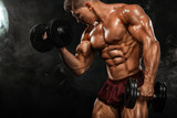 Brutal strong muscular bodybuilder athletic man pumping up muscles with dumbbell on black background. Workout bodybuilding concept. Copy space for sport nutrition ads.