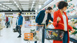 © Gorodenkoff - At the Supermarket: Handsome Man with Smartphone, Pushes Shopping Cart, Walks Through Fresh Produce Section of the Store, Chooses Some Products. Other Customers Purchasing Products.