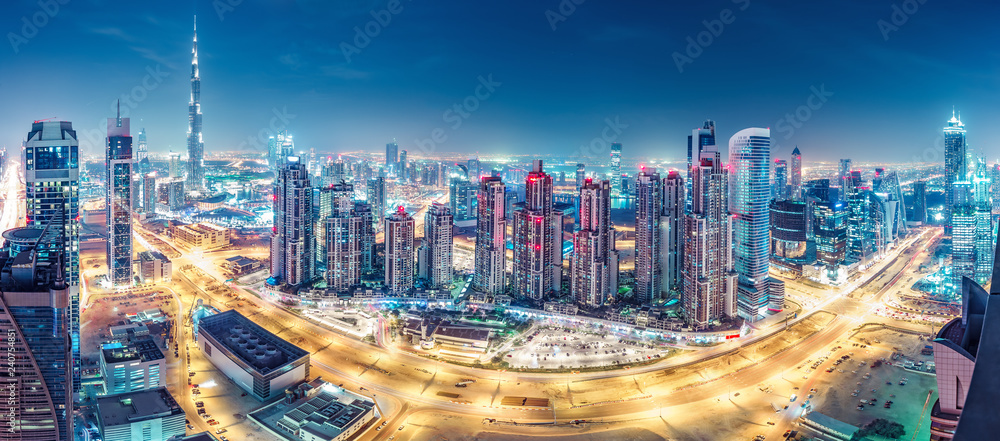 Spectacular urban skyline with colourful city illuminations. Aerial view on highways and skyscrapers of Dubai, United Arab Emirates. - obrazy, fototapety, plakaty 