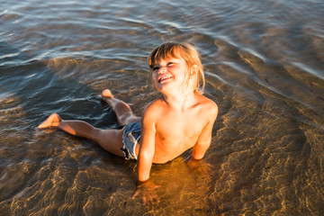 Caucasian blonde little girl on the beach sand at sunset