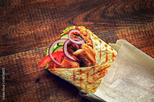 Fotografie, Obraz delicious shawarma with pieces of meat and vegetables on a wooden background, ba