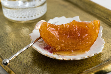 Wall Mural - Home-made orange spoon sweet and glass of cold water on vintage bronze tray.