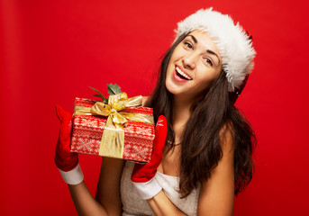 Beautiful smiling young woman in Christmas hat with a gift in hand, close-up