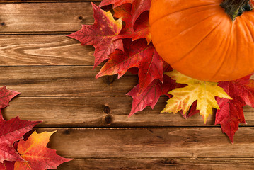 Wall Mural - Pumpkin with red maple leafs disposed on wooden table. Flat lay, top view fall autumn concept.
