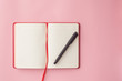 open diary with a pen on a pink background. top view. selective focus. business concept.