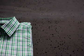 Poster - Top view of a business shirt on a dark, stone table. The concept of fashion and sale of clothes for men, business and luxury shirts. Green plaid shirt on the table.