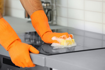 Sticker - Man cleaning kitchen stove with sponge, closeup