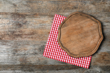 Fabric napkin with serving board and space for text on wooden background, top view