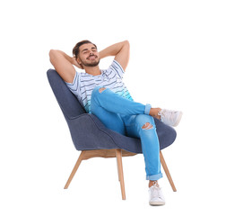 Wall Mural - Handsome young man sitting in armchair on white background