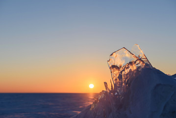 Wall Mural - transparent fragments of ice against the backdrop of the endless snowy landscape during sunset.