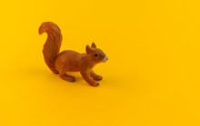 Toy Squirrel From Plastic On A Yellow Background.