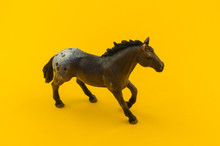 Toy Horse Made Of Plastic On A Yellow Background.