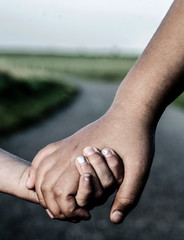 Wall Mural - Refugee girl and white girl holding hands while walking on the road