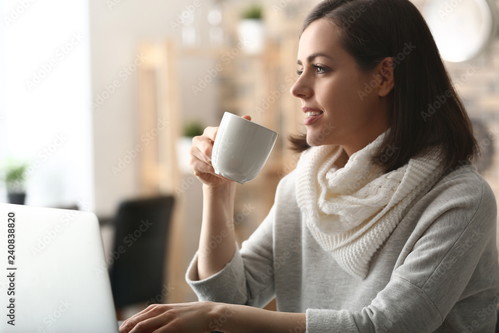 Young woman drinking coffee while working with laptop at home