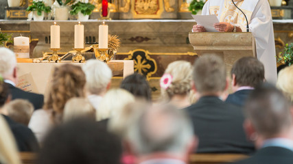 people with preacher are listen and pray in a catholic church