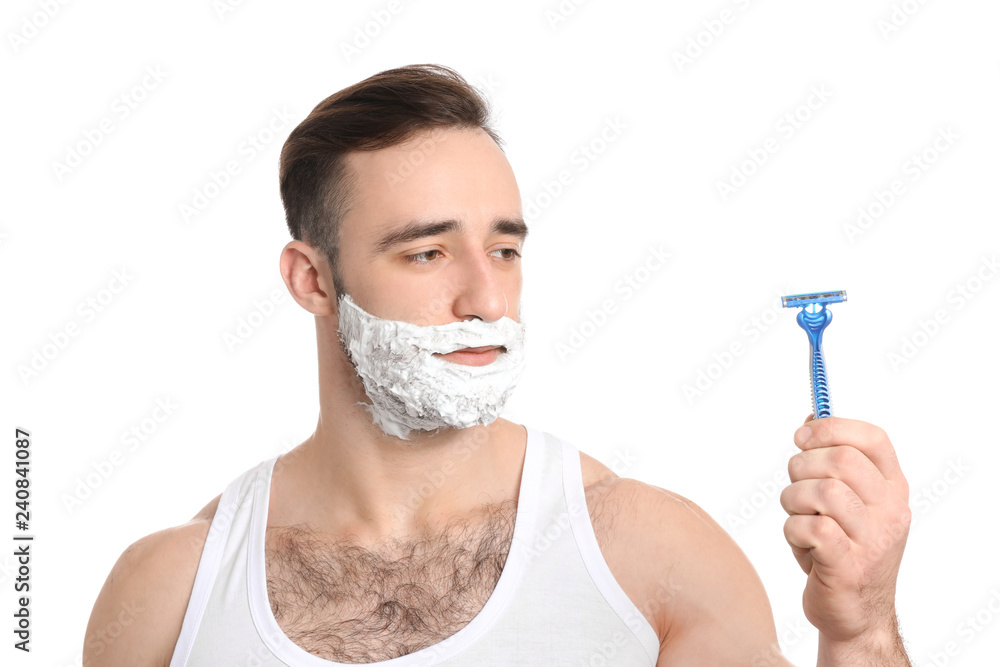 Handsome man with shaving foam on his face and razor against white background