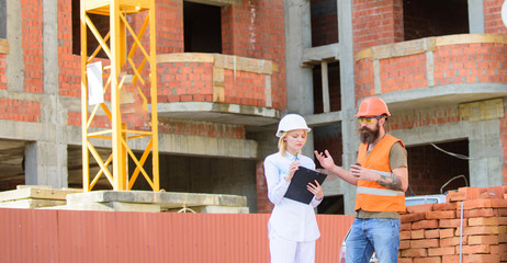 Woman engineer and builder communicate at construction site. Construction team communication concept. Relationships between construction clients and participants building industry. Discussing plan