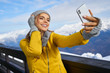 © ZoomTeam - Woman skier making selfie photo on the background of snowy high mountains and