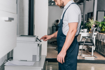 Wall Mural - cropped image of male handyman repairing copy machine in modern office