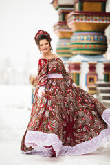 Wall Mural - Beautiful happy woman is wearing traditional russian costume in winter