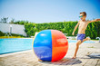 © Westend61 - Shirtless boy playing with beach ball at poolside