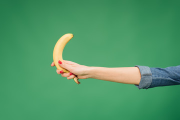 cropped view of woman holding banana in hand isolated on green