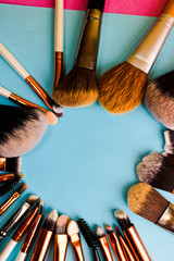 A frame from a set of beautiful different soft makeup brushes from natural lint for targeting beauty and applying a tonal foundation in a stand and copy space on a blue background