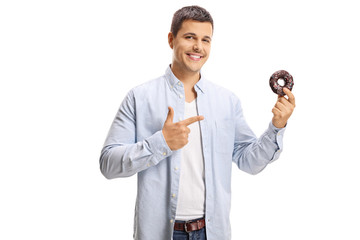 Canvas Print - Smiling young man pointing to a donut in his hand