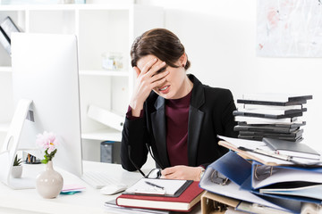 Wall Mural - sad exhausted businesswoman touching forehead at table in office