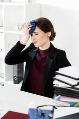 Wall Mural - unhealthy businesswoman touching head with ice pack in office