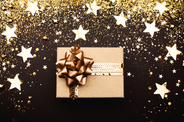 Wall Mural - Gift box with golden bow on black background.