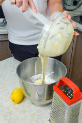 A woman is cooking in her kitchen, about to bake a cake. Makes dough for biscuit - mixes whipped egg whites and yolks