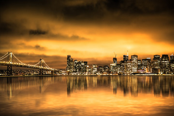 Fototapete - View of San Francisco skyline under golden sunset sky with lights and Bay Bridge