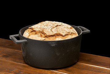 No knead or sourdough hand made bread in black cast iron pot isolated on white background including clipping path