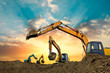 Four excavators work on construction site at sunset