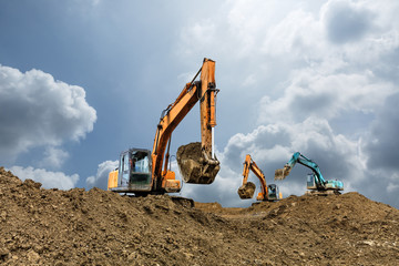 Wall Mural - Excavator working on construction site in cloudy day