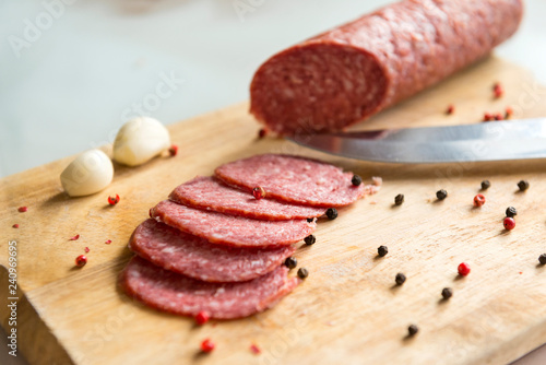 Fotografie, Obraz sliced salami slices with spices and garlic on wooden Board, knife