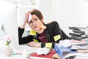 Wall Mural - sad attractive businesswoman sitting with stickers on face and clothes in office