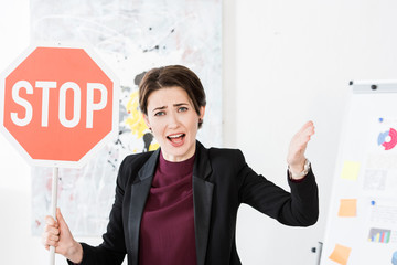 Wall Mural - angry businesswoman holding stop sign and screaming in office