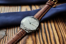 Close Up Of Wristwatch With Leather Strap On Wooden Background, Blue Tie. Details Of The Groom's Fees Before The Wedding
