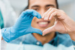 © LIGHTFIELD STUDIOS - selective focus of heart shape hands of dentist and african american patient